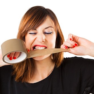 Person using their teeth to tear tape