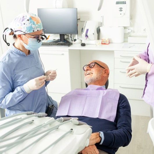 Senior patient conversing with his dental team