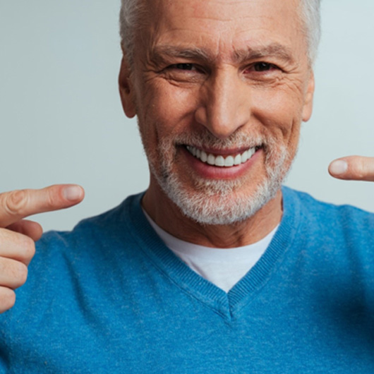 Happy senior man pointing at his dentures