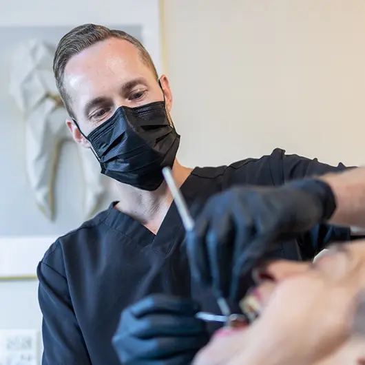 Cleaning female dental patient's teeth with electric brush