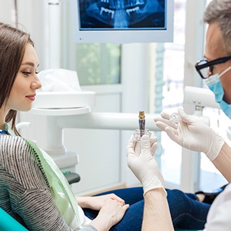 Dentist showing patient a sample dental implant and its parts