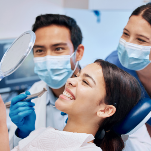 Female dental patient checking smile in handheld mirror