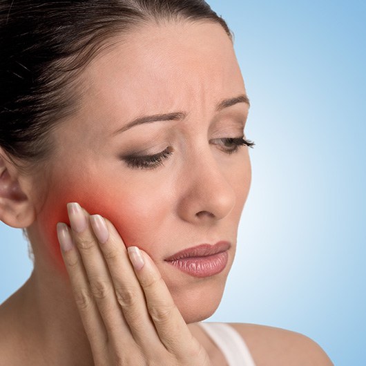 a dental patient holding her cheek in pain